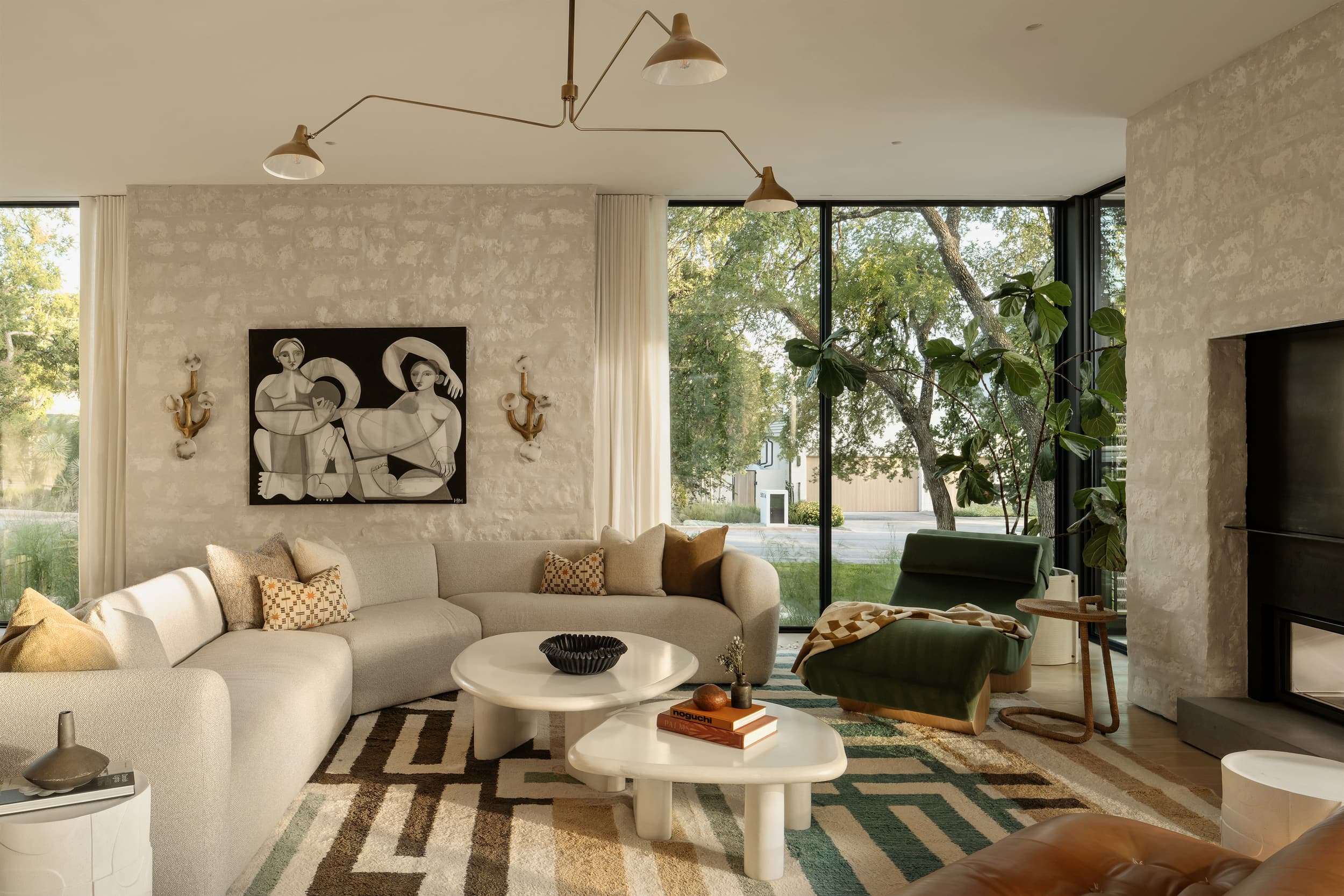 A bright, modern living room with a white sectional sofa, patterned rug, and a large window.