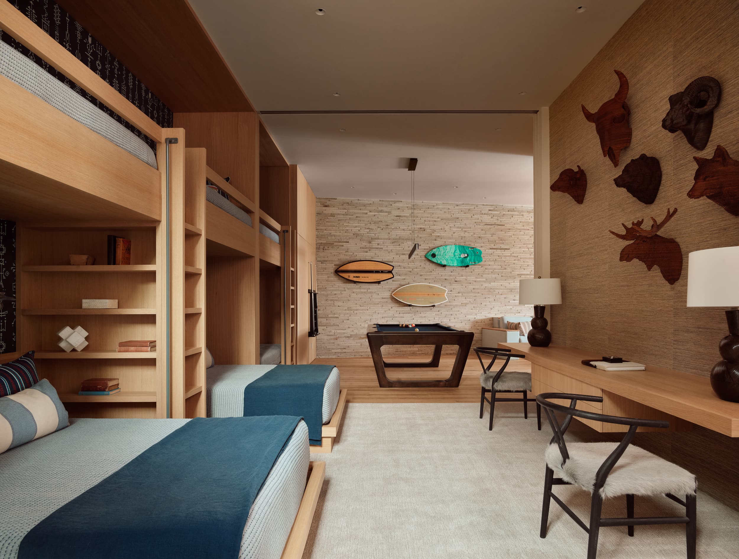 A rustic-modern bedroom with light wood bunk beds and a wall decorated with carved animal heads.